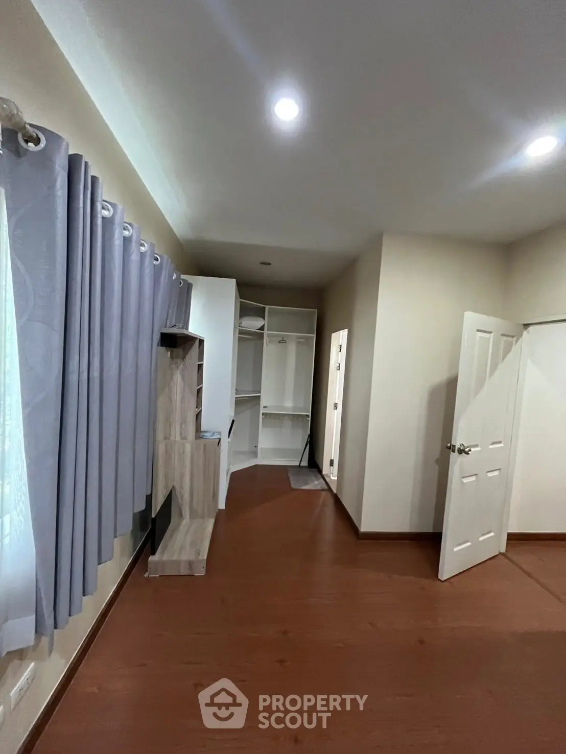 Spacious bedroom with wooden flooring and built-in closet, perfect for modern living.