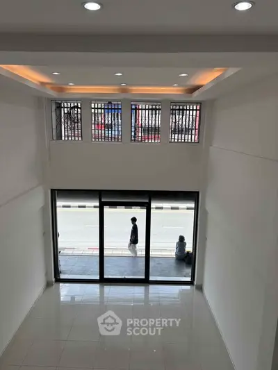 Spacious modern interior with high ceilings and large windows offering street view.