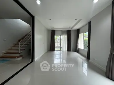 Spacious modern living room with large windows and staircase view