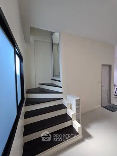 Sleek modern staircase with contrasting black and white steps in a bright, minimalist interior space, perfect for contemporary homes.