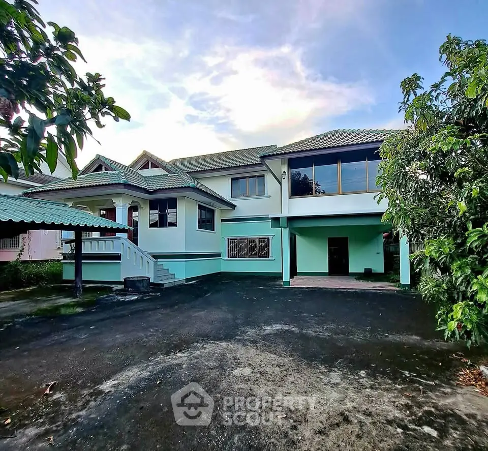 Spacious two-story house with lush greenery and ample parking space, perfect for family living.