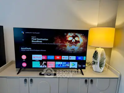 Modern living room with sleek TV setup and stylish lamp on a chic cabinet.
