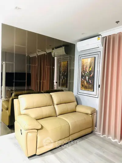 Modern living room with beige leather sofa and mirrored wall, featuring elegant decor and air conditioning.