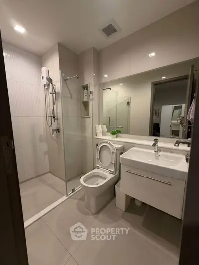 Modern bathroom with glass shower, sleek vanity, and contemporary fixtures.