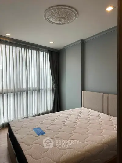 Spacious bedroom with elegant ceiling design and large window for natural light.