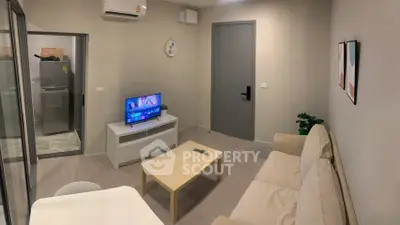 Cozy living room with modern decor and neutral tones, featuring a comfortable sofa and flat-screen TV.