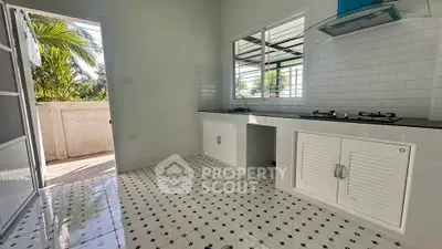 Bright kitchen with open layout and gas stove, leading to a sunny balcony.