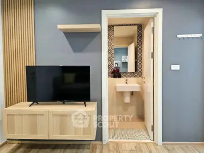 Modern living room with TV and open view into stylish bathroom