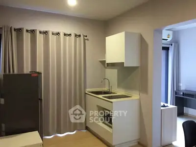 Modern compact kitchen with sleek cabinetry and integrated appliances in a cozy apartment setting.