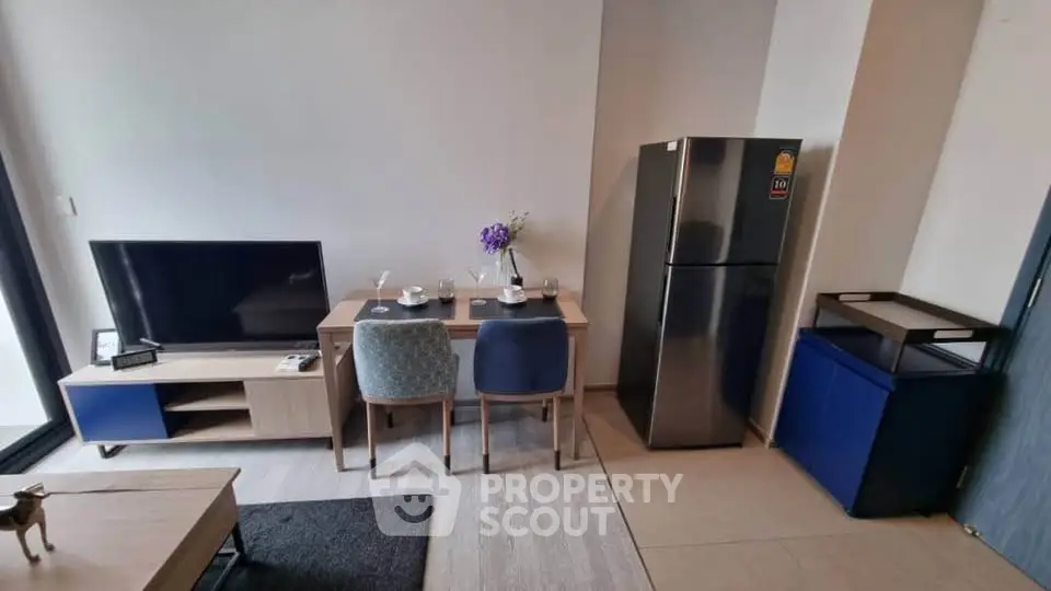 Modern living room with dining area and stainless steel fridge in a cozy apartment.