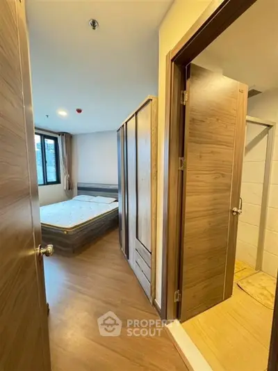Modern bedroom with wooden flooring and ensuite bathroom in a stylish apartment.