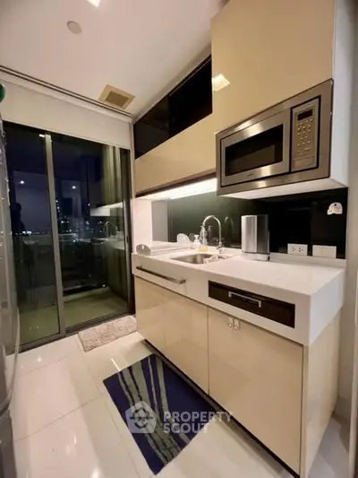 Modern kitchen with sleek cabinetry and built-in microwave, featuring a city view from the balcony.