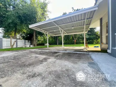 Spacious outdoor carport with lush green surroundings and ample parking space