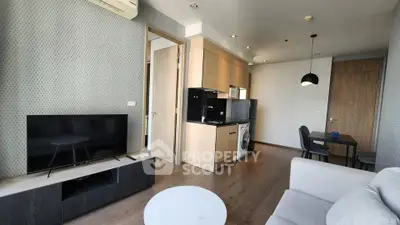 Modern living room with open kitchen, featuring sleek furniture and contemporary design.