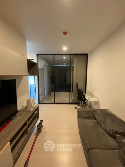 Modern living room with sleek design and glass partition, featuring a cozy sofa and entertainment unit.