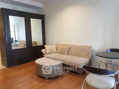 Cozy living room with modern furniture and wooden flooring, featuring a stylish wardrobe and comfortable seating.