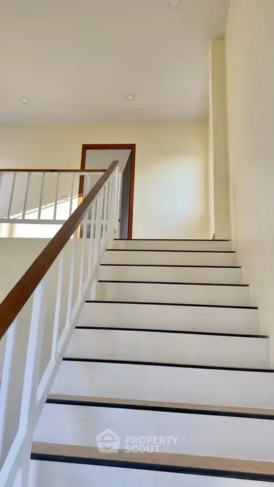 Modern staircase with wooden handrail in bright interior space