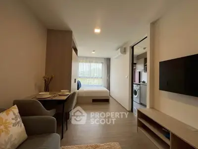 Modern studio apartment with open layout, featuring a cozy living area, dining space, and a compact kitchen with washing machine.
