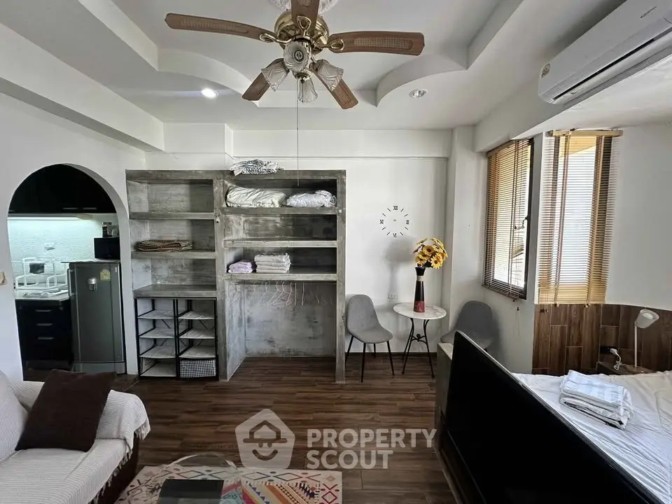 Charming studio apartment with modern decor, featuring a cozy living area, stylish ceiling fan, and compact kitchen.