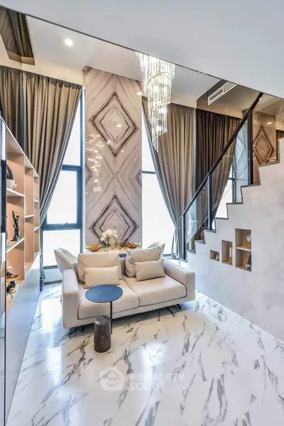 Luxurious modern living room with high ceilings, elegant chandelier, and stylish staircase in a contemporary apartment.