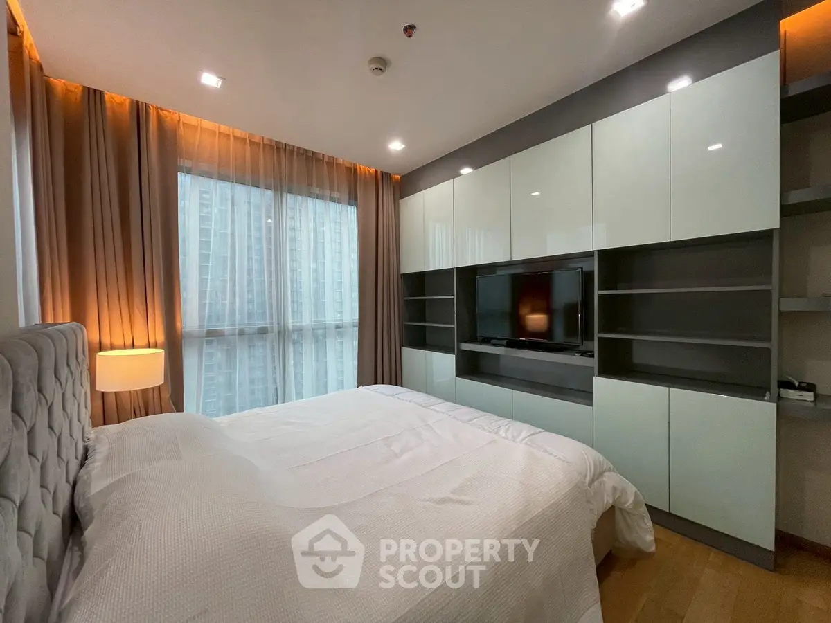 Luxurious modern bedroom with built-in storage and large window in high-rise apartment.