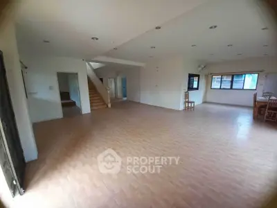 Spacious open-plan living area with tiled flooring and staircase