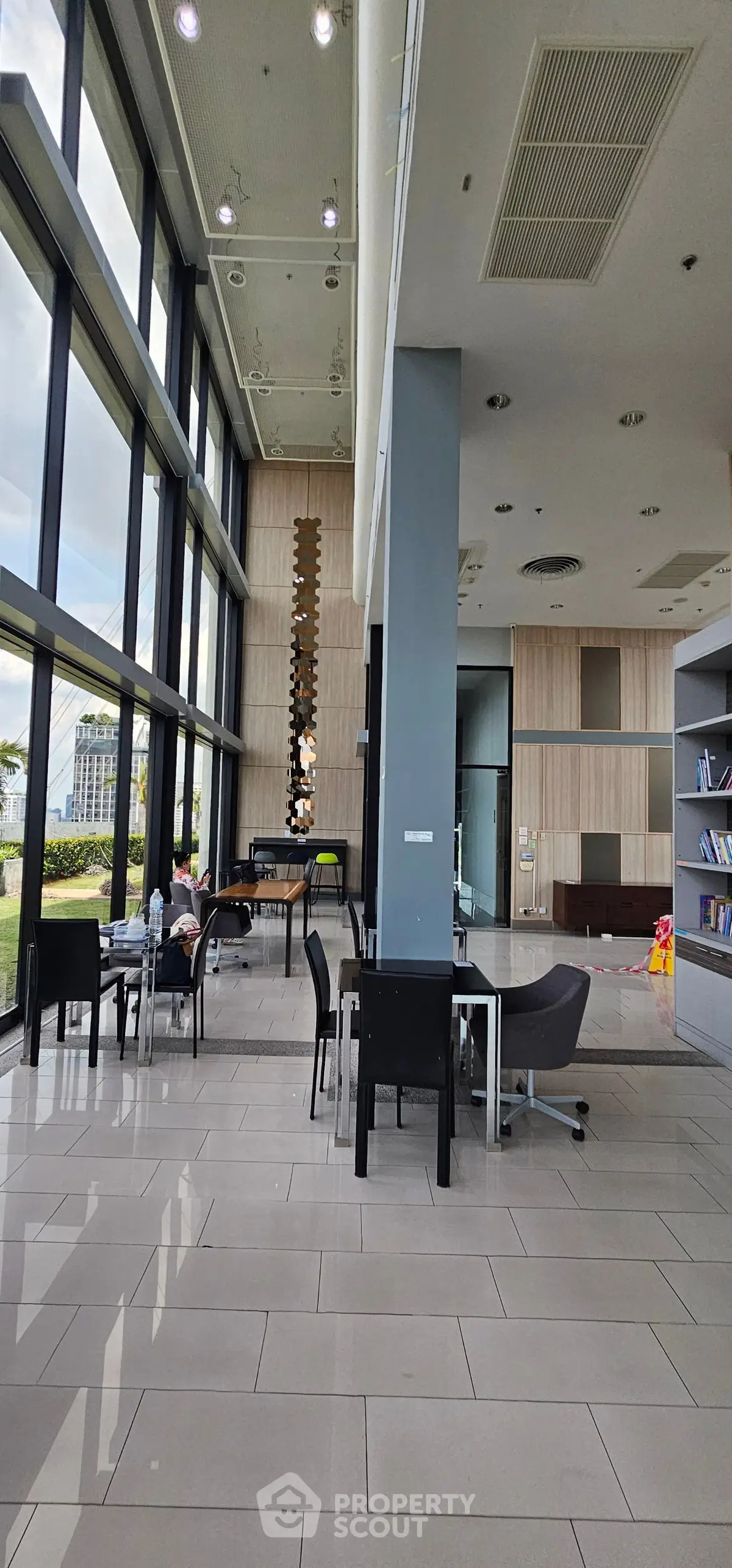 Modern building lobby with high ceilings and large windows, featuring stylish seating and decor.