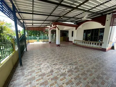 Spacious covered patio with tiled flooring and garden view, perfect for outdoor gatherings.