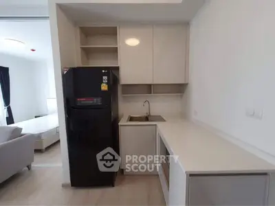 Modern kitchen with sleek cabinets and black fridge in open layout apartment.