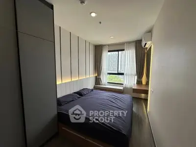 Modern bedroom with sleek design and large window offering natural light.
