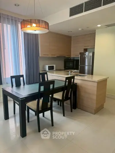 Modern kitchen with dining area, featuring sleek cabinetry and stainless steel appliances.