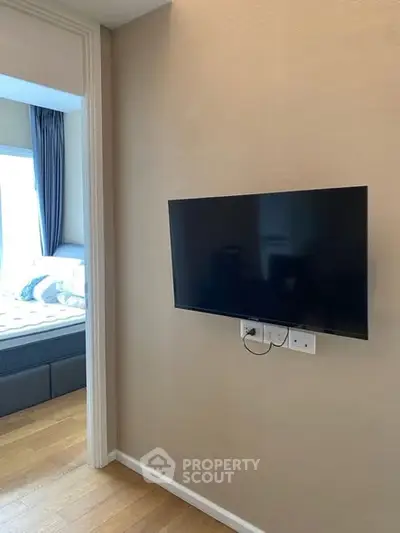 Modern bedroom with wall-mounted TV and wooden flooring