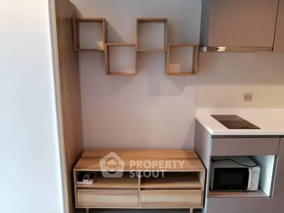 Modern kitchen with sleek cabinetry and built-in microwave, featuring minimalist wooden shelving.