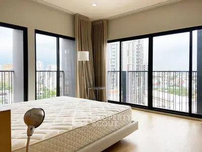 Spacious bedroom with large windows offering stunning city views in a modern apartment.