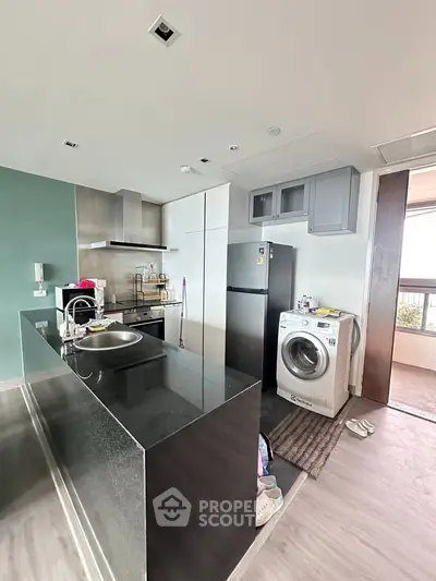 Modern kitchen with sleek black countertops and integrated appliances in a stylish apartment.