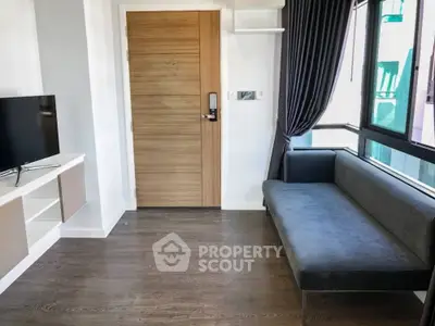Modern living room with sleek sofa and wall-mounted TV, featuring wooden flooring and large window.