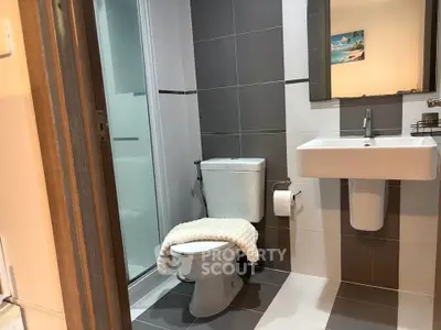 Modern bathroom with sleek design and neutral tones, featuring a shower and contemporary fixtures.