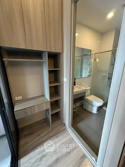 Modern bathroom with sleek design and wooden cabinetry, featuring a glass shower enclosure.