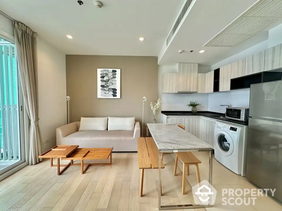 Modern open-plan living room with kitchen, featuring sleek furniture and appliances.