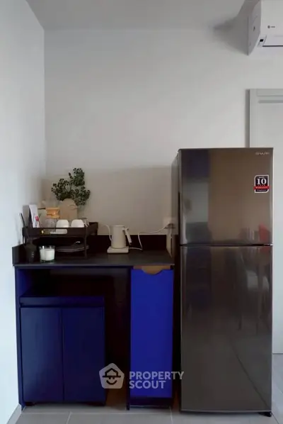 Modern kitchen with sleek fridge and minimalist design, perfect for compact living spaces.
