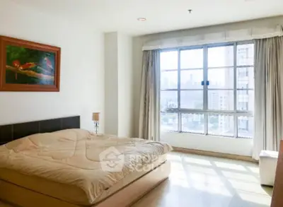 Spacious bedroom with large window offering stunning city views and natural light.