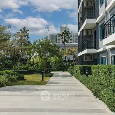 Modern apartment building with lush garden and clear sky view