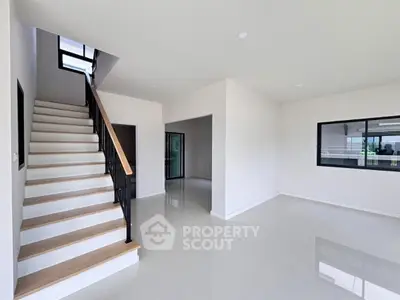 Spacious modern interior with sleek staircase and large windows, perfect for contemporary living.