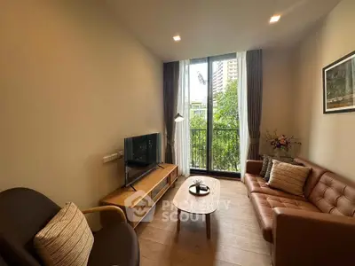 Cozy living room with modern furniture and large window offering lush green view.