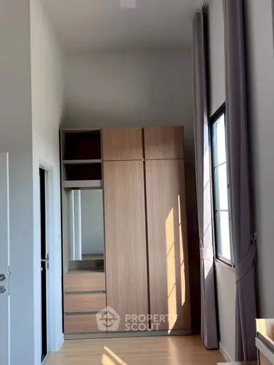 Spacious bedroom with modern wardrobe and large window for natural light