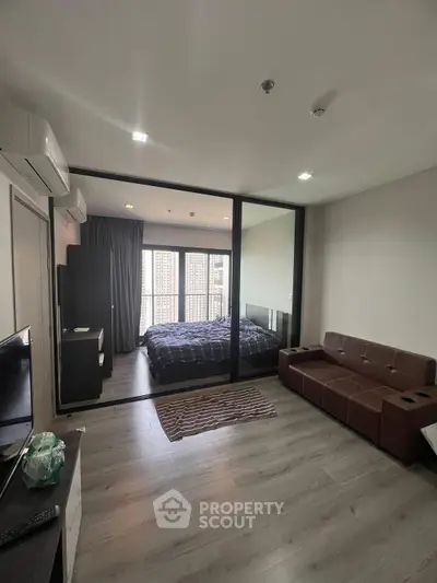 Modern studio apartment with glass partition and cozy furnishings.