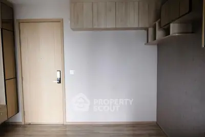 Modern minimalist room with wooden flooring and built-in storage cabinets.