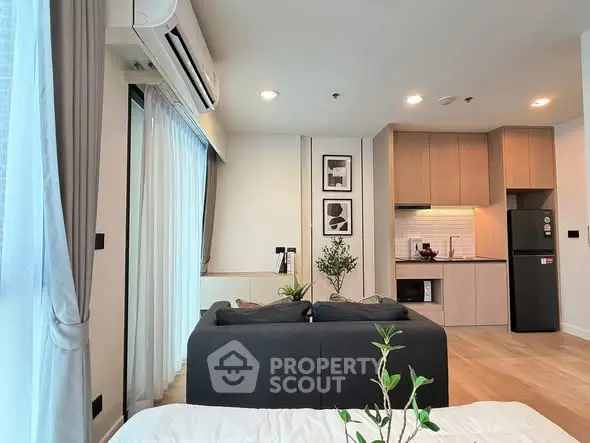 Modern living room with open kitchen, featuring sleek design and natural light.