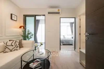 Modern living room with stylish decor and view into a cozy bedroom, featuring elegant furnishings and natural light.