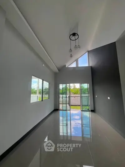 Spacious modern living room with high ceiling and large windows offering natural light.